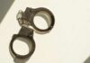 College Hoops FIXER Nailed A pair of metallic handcuffs resting on a light surface