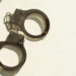 College Hoops FIXER Nailed A pair of metallic handcuffs resting on a light surface