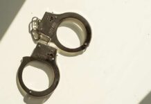 College Hoops FIXER Nailed A pair of metallic handcuffs resting on a light surface