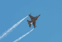 F-16s ROAR Over Rally Fighter jet banking in flight with vapor trails
