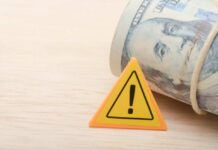 $930M War Chest Blindside Parents A roll of cash next to a warning sign on a wooden surface