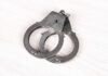 Trump Plot Triggers Arrest A pair of metallic handcuffs resting on a light wooden surface
