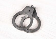 Trump Plot Triggers Arrest A pair of metallic handcuffs resting on a light wooden surface