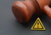 Feds Hit Dem’s Home – Judge Signed Off Wooden gavel with a yellow warning triangle sign on dark surface