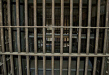SHOCKING: Murderer On The Loose Empty, rusty barred jail cell with metal bunks.