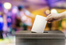 Bold Line Sparks 2028 Buzz Hand placing ballot in voting box.